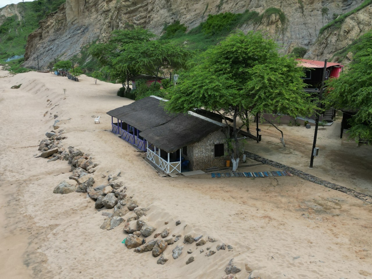 Casa rústica na praia cercada por árvores e rochas